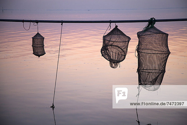 Silhouette von Fischernetzen über stillem Wasser