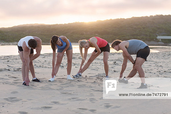 Runners stretching on beach