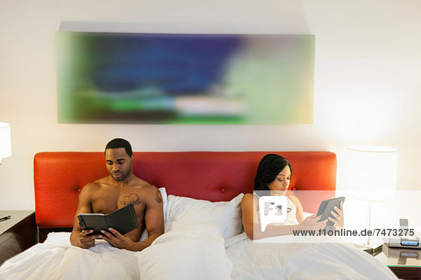 Couple using e-readers in bed