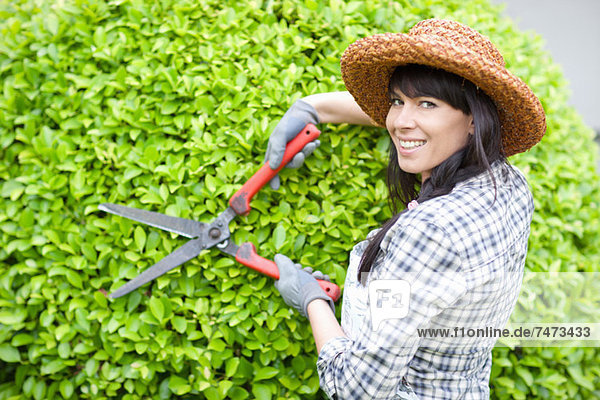 Frau beim Heckenschneiden im Garten