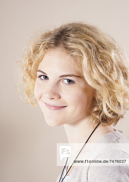 Close-up Portrait of Blond  Teenage Girl with Curly Hair  Smiling at Camera  Studio Shot on White Background