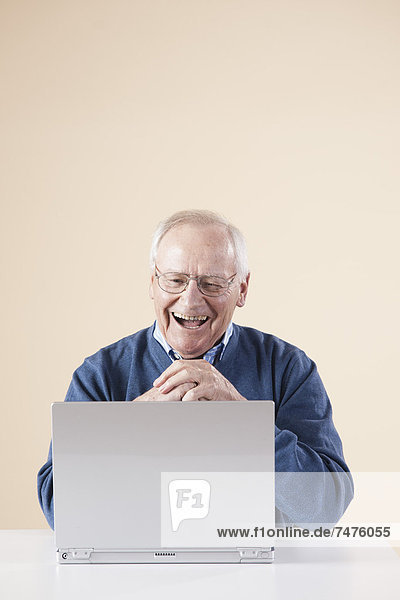 sitzend  Senior  Senioren  Mann  Computer  Notebook  sehen  lachen  Tisch