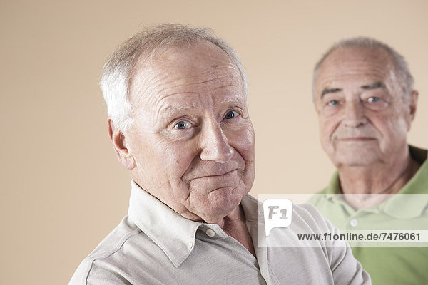 Portrait of Two Senior Men Looking at Camera  Studio Shot on Beige Background
