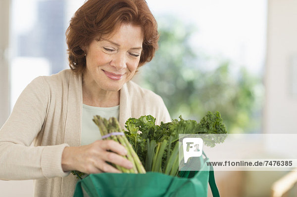 Senior woman with groceries in kitchen