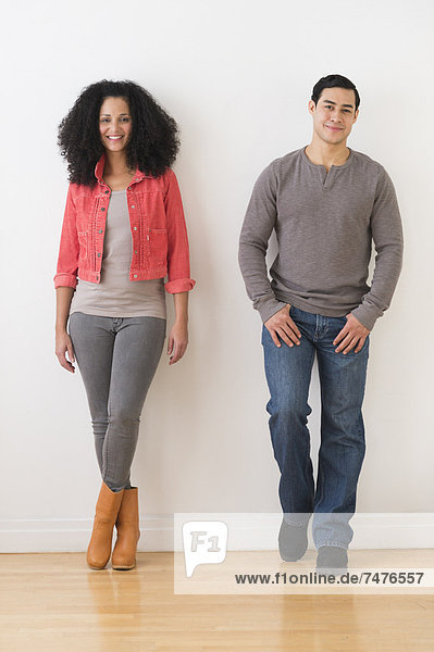 Smiling couple standing against white wall