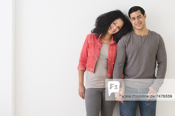 Portrait of smiling couple standing against white wall