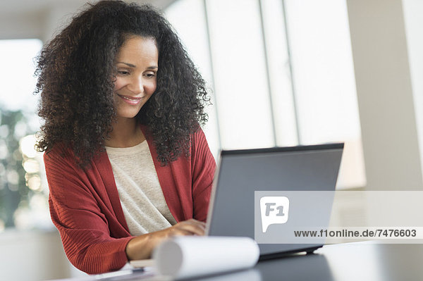 Smiling mid adult woman doing home finances with laptop