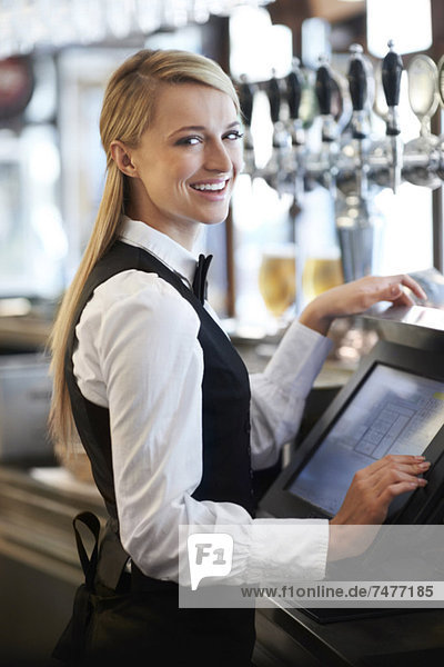 Young waitress using computer at restaurant counter