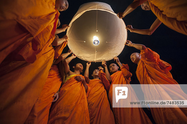 Monks releasing a Kongming lantern or sky lantern for luck during the Loi Krathong or Loy Gratong Festival  Chiang Mai  Northern Thailand  Thailand  Asia
