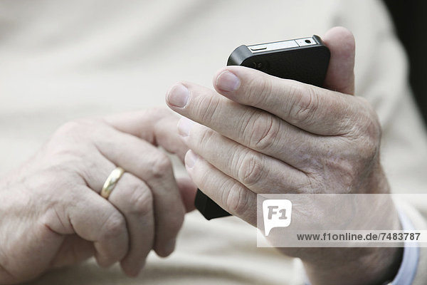 Senior hält Smartphone in den Händen