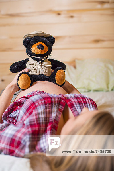 USA  Texas  Schwangere junge Frau mit Teddybär auf dem Bauch