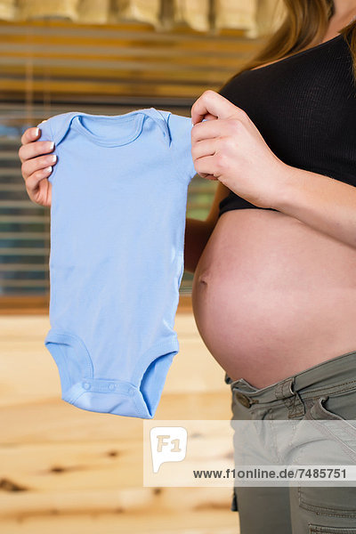 USA  Texas  Schwangere junge Frau mit Babykleidung  Nahaufnahme
