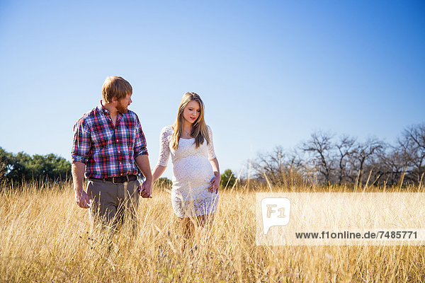 USA  Texas  Mann und schwangere Frau beim Gehen im Gras
