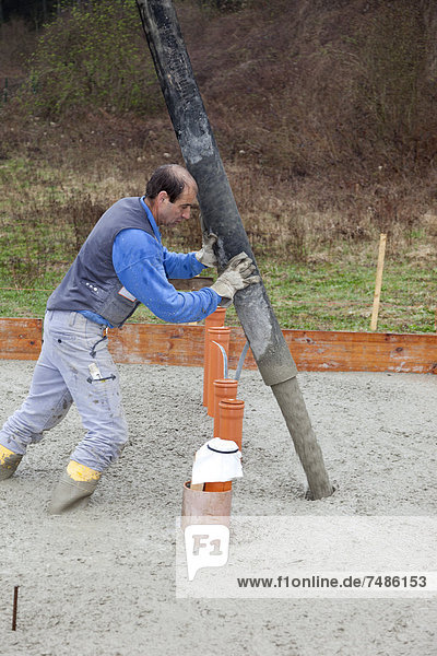 Europa  Deutschland  Rheinland-Pfalz  Mann füllt Beton in Schalung für Fundament