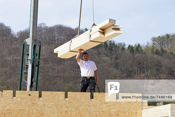 Europa  Deutschland  Rheinland-Pfalz  Mann montiert und befestigt Holzwände von Fertighäusern