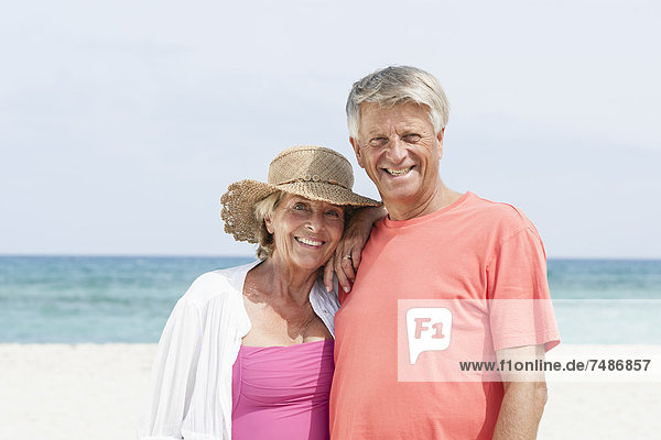 Spanien  Seniorenpaar am Strand stehend  lächelnd  Portrait