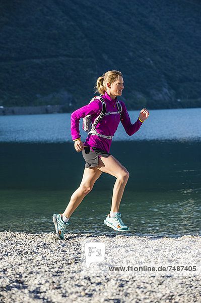 Italy  Mid adult woman jogging by Lake Garda