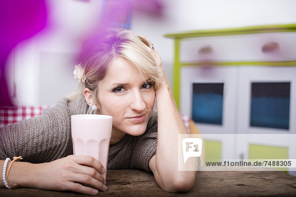 Porträt einer jungen Frau am Tisch sitzend mit Kaffee