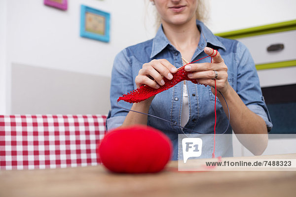 Junge Frau strickt mit rotem Garn