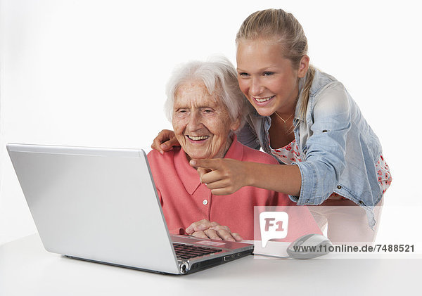 Senior woman and teenage girl using laptop  smiling