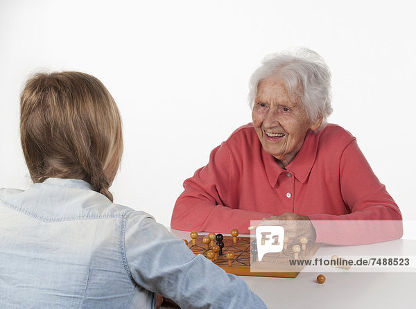 Senior woman and teenage girl playing Fox And Hen Game  smiling