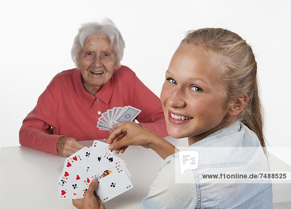 Senior woman and teenage girl playing cards  smiling