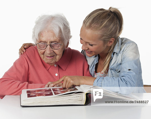 Senior woman and teenage girl watching photo album  smiling