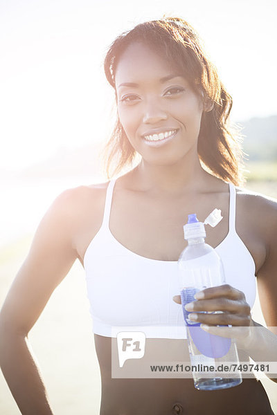 Mixed race woman drinking water bottle