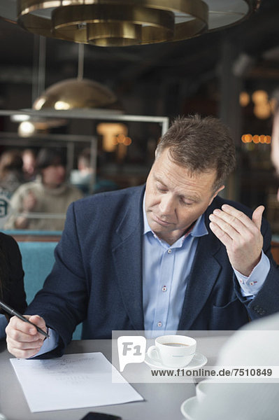 Erwachsener Mann schreibt auf Papier am Restauranttisch
