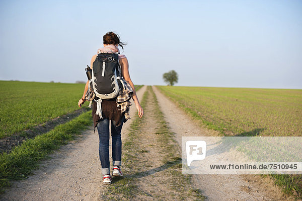 Rückansicht einer jungen Frau mit Rucksack auf einem Wanderweg