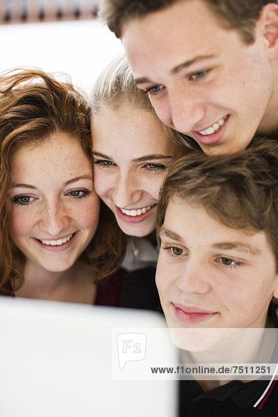 Glückliche junge Freunde schauen auf den Laptop-Bildschirm