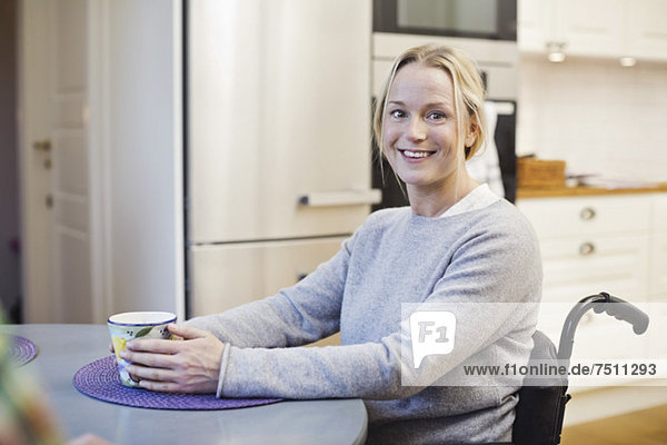 Porträt einer glücklichen behinderten Frau mit Kaffeetasse in der Küche