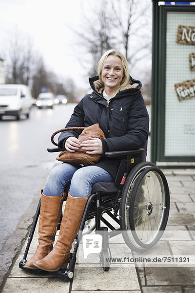 Porträt einer glücklichen behinderten Frau im Rollstuhl lächelnd im Freien