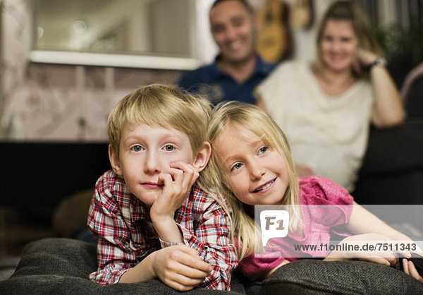 Porträt eines kleinen Jungen  der mit seiner Schwester vor dem Fernseher liegt.
