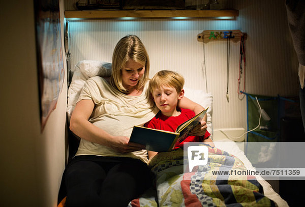 Mother and son reading book together in bed
