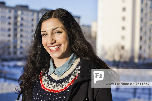 Porträt einer glücklichen jungen Frau aus dem Nahen Osten mit Gebäude im Hintergrund