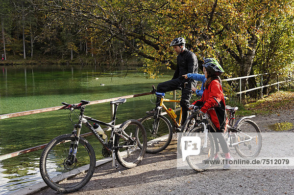 Father and children riding mountain bikes  at Badersee lake in Grainau  Werdenfelser Land  Upper Bavaria  Bavaria  Germany  Europe