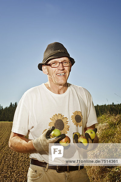 Mann mit Äpfeln auf dem Feld
