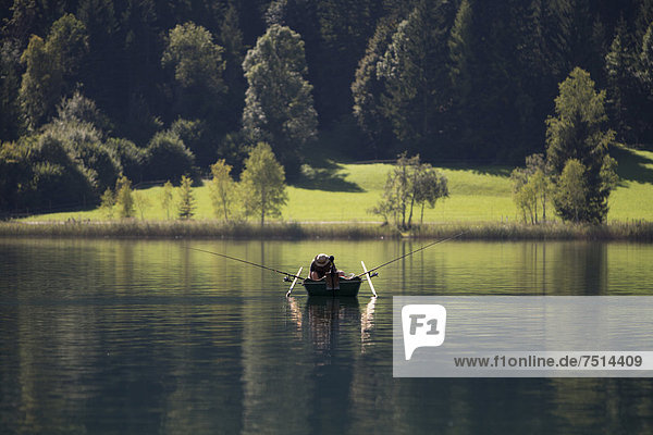 Ein Angler in seinem Ruderboot am Morgen auf dem Weißensee  Kärnten  Österreich  Europa