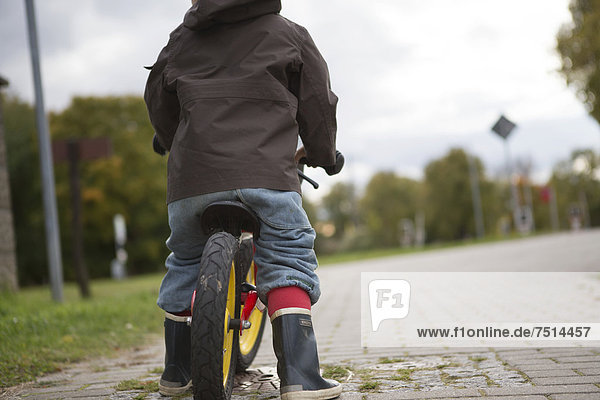 A young boy is practicing to ride a bicycle on a quiet street  Brandenburg  Germany  Europe