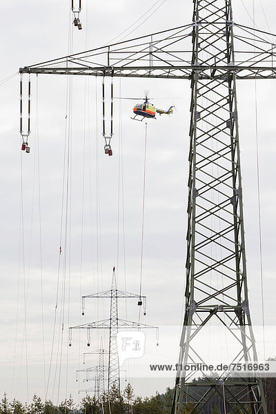 Vorseilzugarbeiten an der 380-kV-Fernleitung des Übertragungsnetzbetreibers 50Hertz  per Helikopter werden Leitungsseile von Mast zu Mast gezogen  mit denen später die eigentlichen elektrischen Leiterseile montiert werden  Gudow  Schleswig-Holstein  Deutschland  Europa