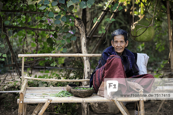 Elderly woman sitting on a bench made of bamboo  Myanmar  Burma  Southeast Asia  Asia