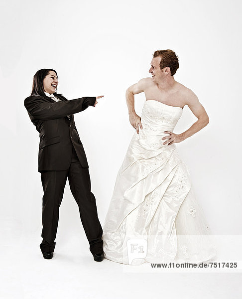 Bride wearing a suit laughing at a groom wearing a wedding dress