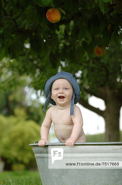 Baby  einjährig  badet in Zinkwanne im Freien