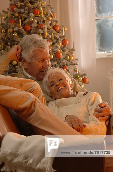 Mature couple in love lying on a sofa in front of a Christmas tree