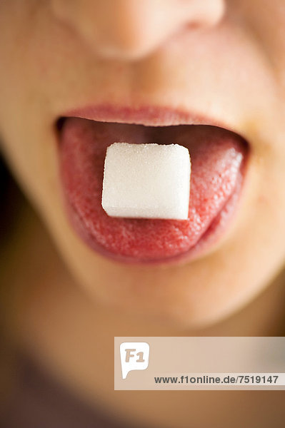 Frau mit einem Zuckerwürfel auf ihrer Zunge