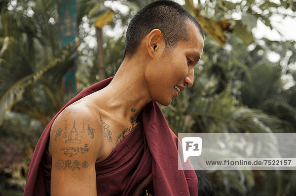 Smiling Buddhist monk with tattoos collecting alms in the morning  portrait  temple and monastery of Wat Phra Archa Thong or Golden Horse Temple  Mae Chan  Chiang Rai Province  Northern Thailand  Thailand  Asia