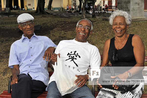 Three Cubans sitting on a park bench  Santa Clara  Cuba  Greater Antilles  Caribbean  Central America  America