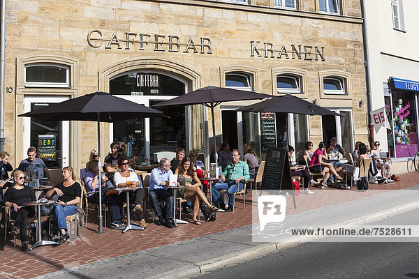 Touristen sitzen bei Sonnenschein in einem Straßencafe  Bamberg  Oberfranken  Franken  Bayern  Deutschland  Europa  ÖffentlicherGrund