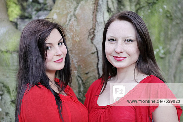 Two sisters in front of an old tree  portrait